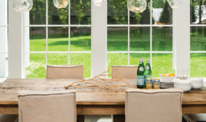 Two large white windows behind a farmhouse style dining table