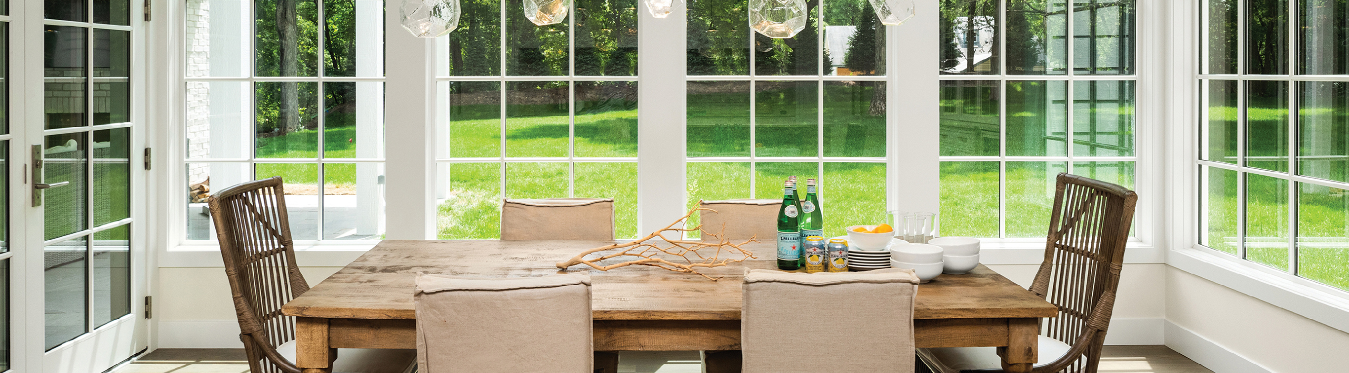 Two large white windows behind a farmhouse style dining table