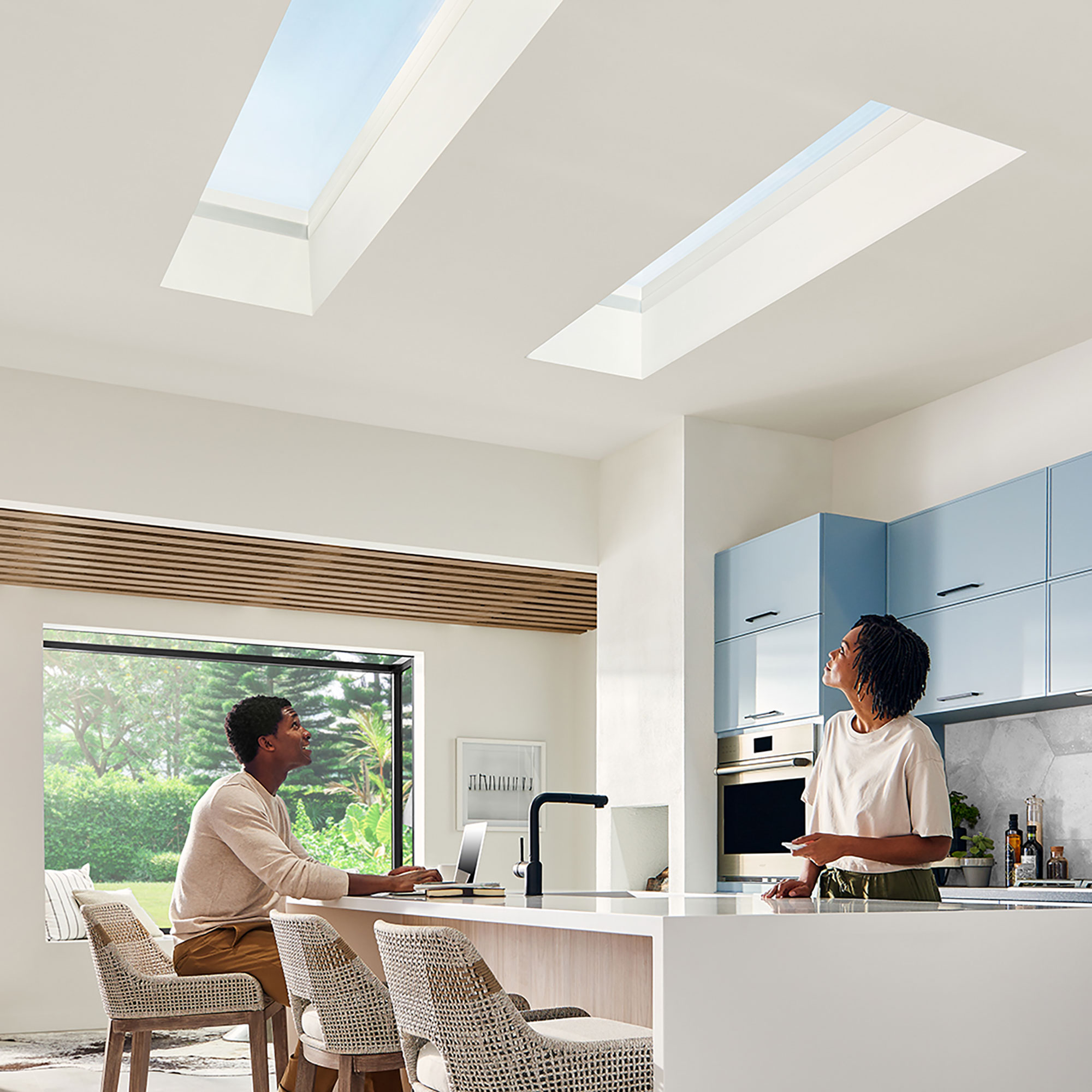 Two adults look up at their skylights in the kitchen ceiling