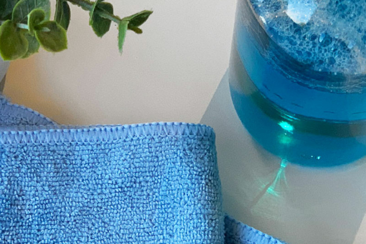 Blue window cleaner and a soft terry cloth rag for cleaning your windows.