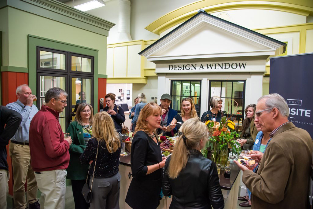 A crowd of happy people enjoy food and drink at an event