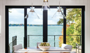 four black framed modern looking doors allow the ocean view to enter the comfortable dining room