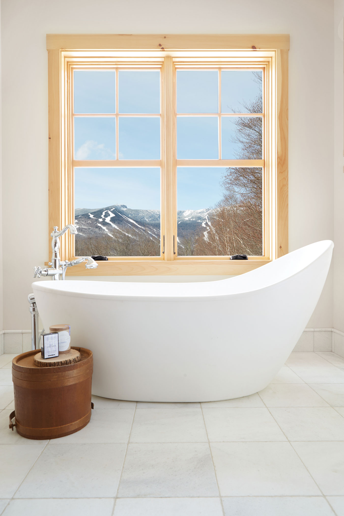 A large bathtub sits below two large double-hung windows