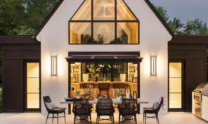 A cathedral style window on a contemporary out building by a pool at night