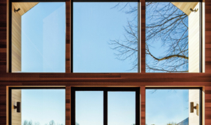 a grid of wooden windows and doors fill a full two story wall of a home