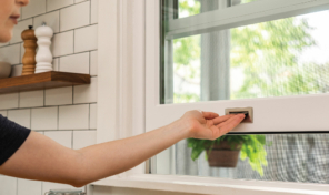 A hand lifts a white and chrome trimmed window