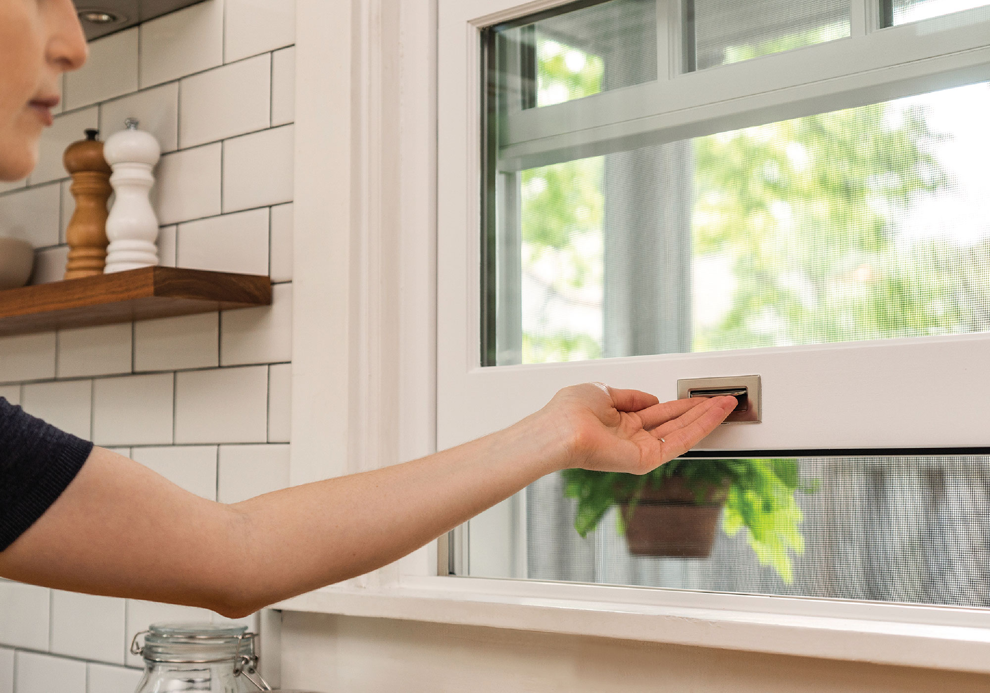 A hand lifts a white and chrome trimmed window